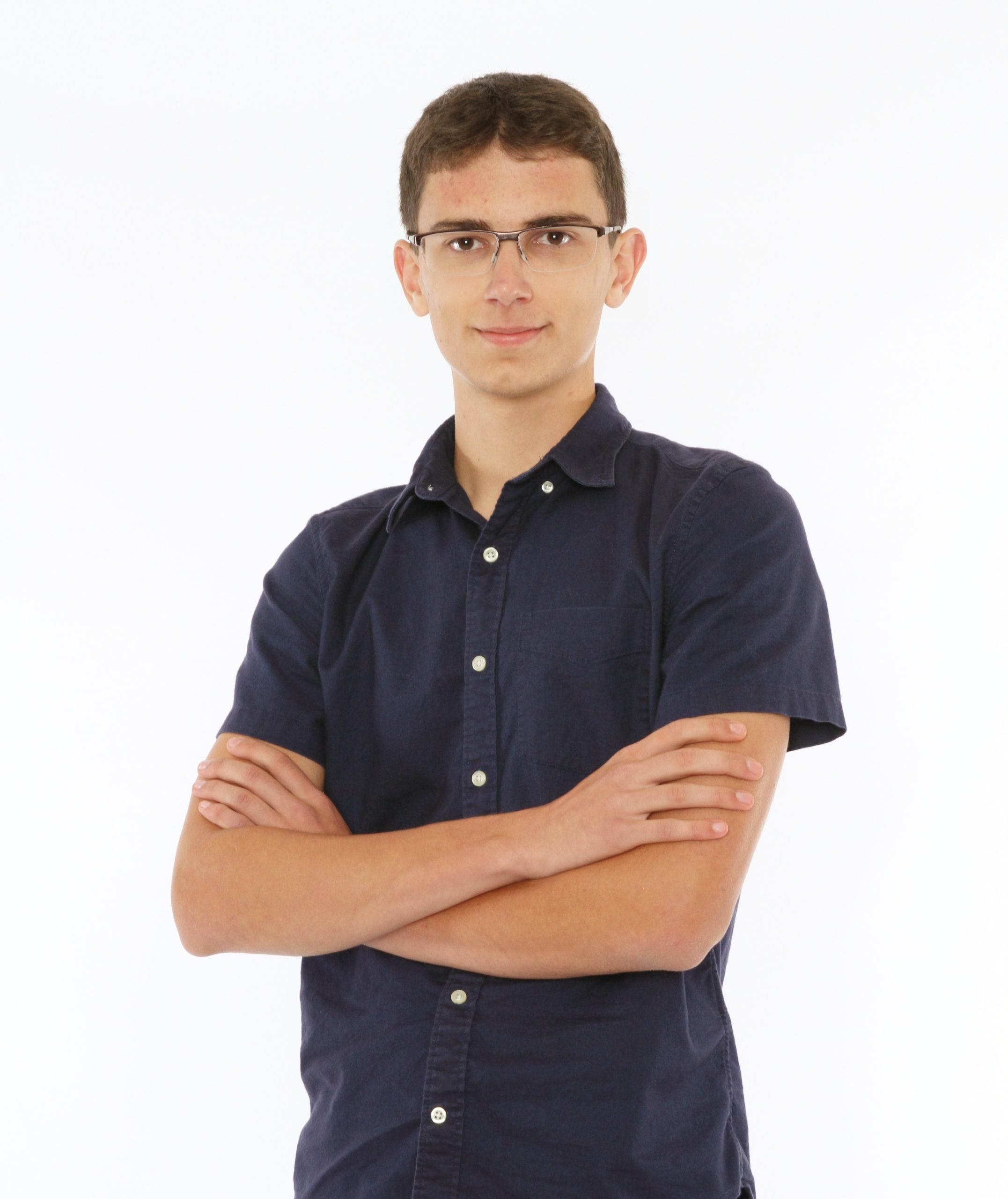 Colten standing with his arms crossed. He is wearing a blue collared shirt and glasses.