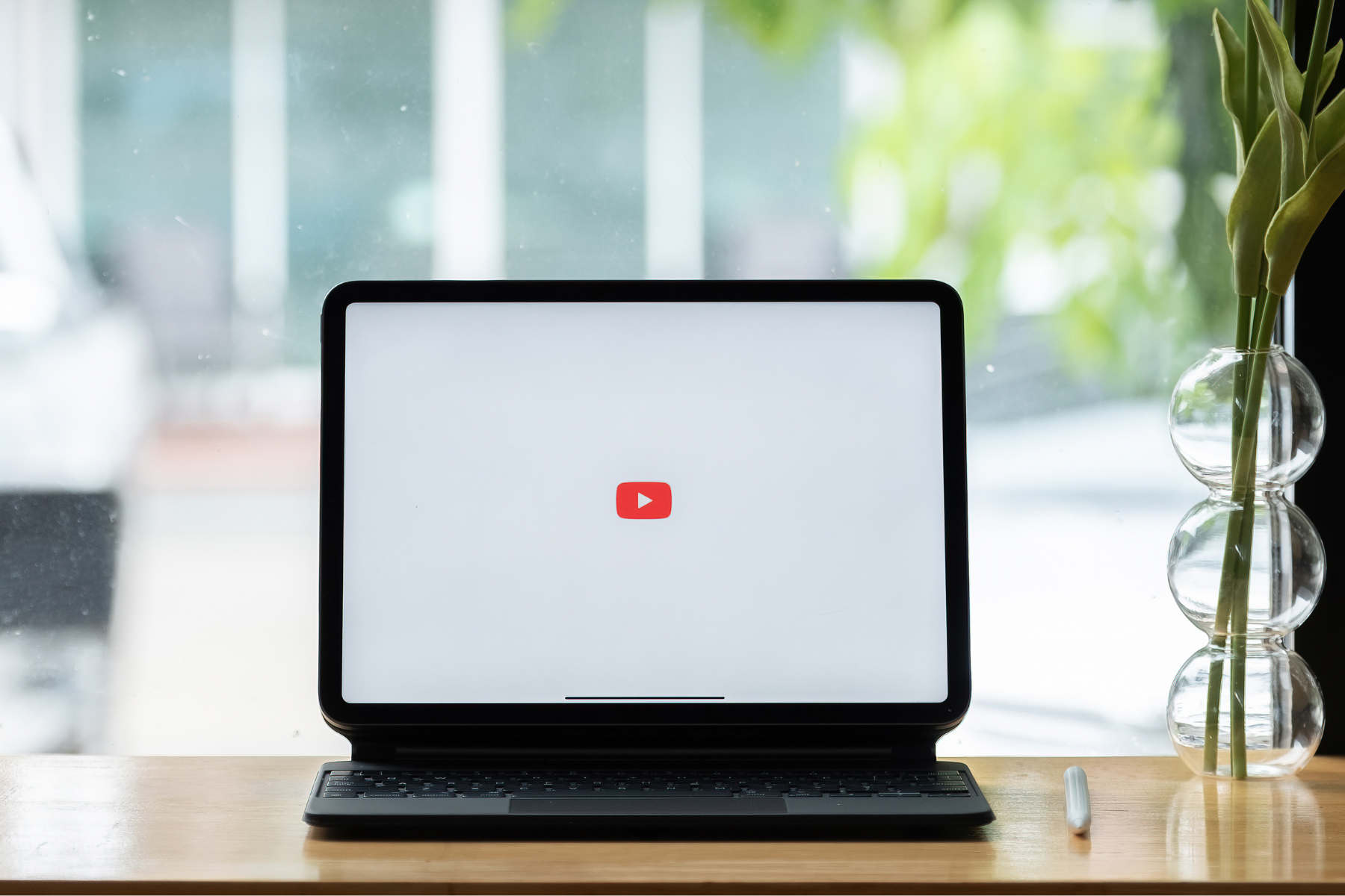 A laptop sitting in the window with the Youtube logo on the screen.